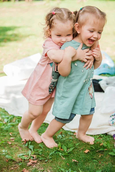 The two little baby girls playing against green grass — Stock Photo, Image