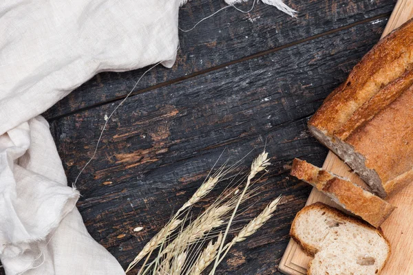 Rustika bröd på bord av trä. Mörk woody bakgrund med fri text utrymme. — Stockfoto