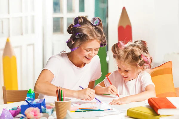 Молодая мать и ее маленькая дочь рисуют карандашами дома — стоковое фото