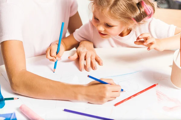 A jovem mãe e sua filhinha desenhando com lápis em casa — Fotografia de Stock
