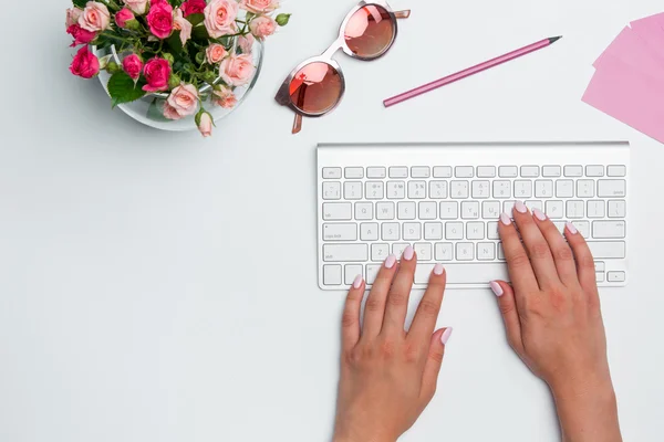 Office desk table with female hands, computer, supplies, flowers — Stock Photo, Image