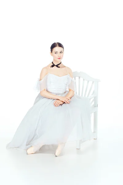 白いドレスに座って、スタジオの背景のバレリーナ. — ストック写真