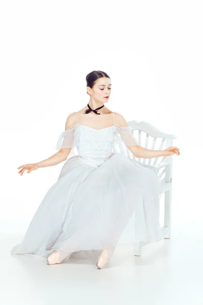 Baletka v bílých šatech sedící, studio pozadí. — Stock fotografie