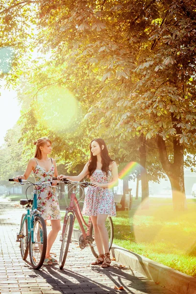 De twee jonge meisjes met fietsen in park — Stockfoto