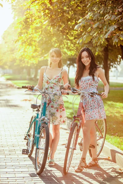 De twee jonge meisjes met fietsen in park — Stockfoto