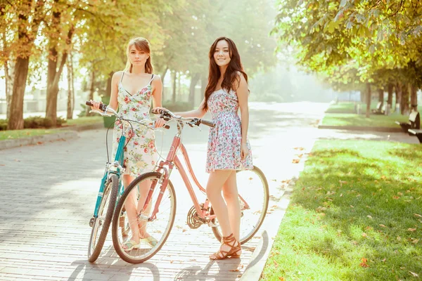 De twee jonge meisjes met fietsen in park — Stockfoto