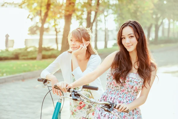 De twee jonge meisjes met fietsen in park — Stockfoto