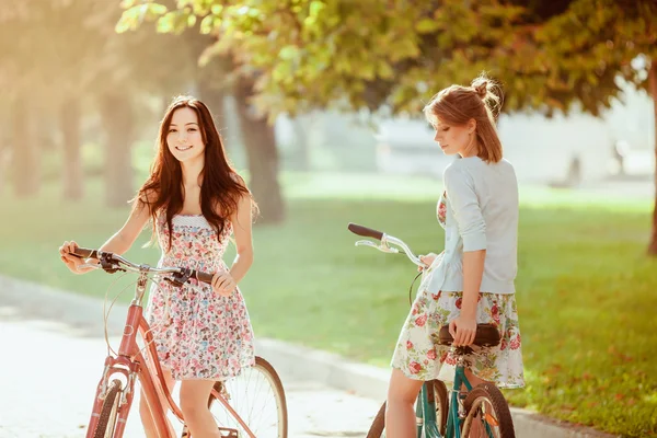 De twee jonge meisjes met fietsen in park — Stockfoto