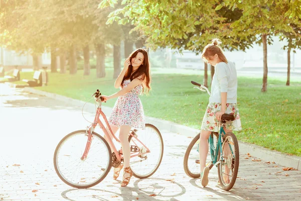 A két fiatal lány a parkban a kerékpár — Stock Fotó