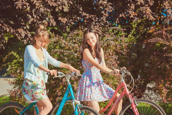 De twee jonge meisjes met fietsen in park — Stockfoto