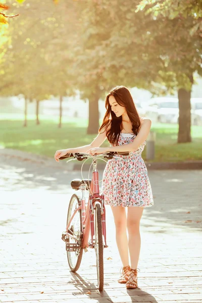 Молодая девушка с велосипедом в парке — стоковое фото