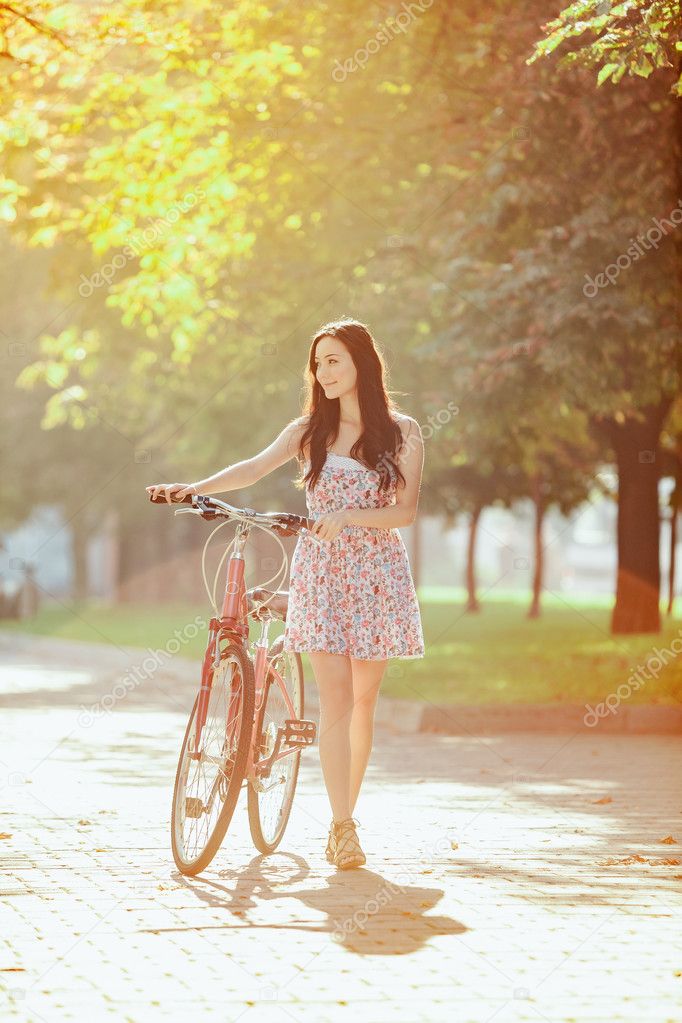 The young girl with bicycle in park