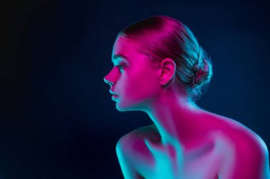 Karanlık stüdyo arka planında neon ışıklı kadın model portresi.