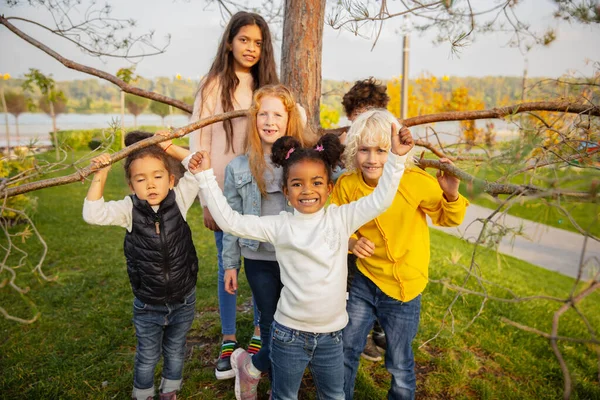 Interracial group of kids, girls and boys playing together at the park in summer day