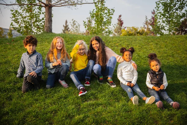 Interracial group of kids, girls and boys playing together at the park in summer day