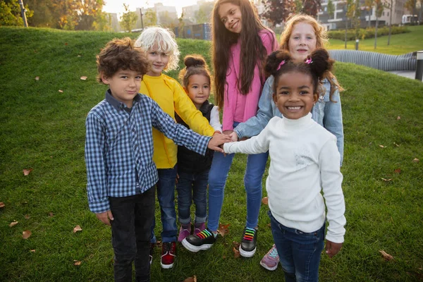 Interracial group of kids, girls and boys playing together at the park in summer day