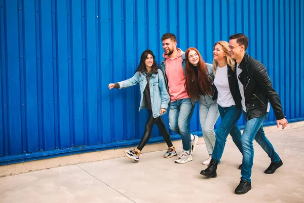 Grupa czterech młodych, zróżnicowanych przyjaciół w stroju Jeanse wygląda beztrosko, młodo i szczęśliwie na ulicach miasta — Zdjęcie stockowe