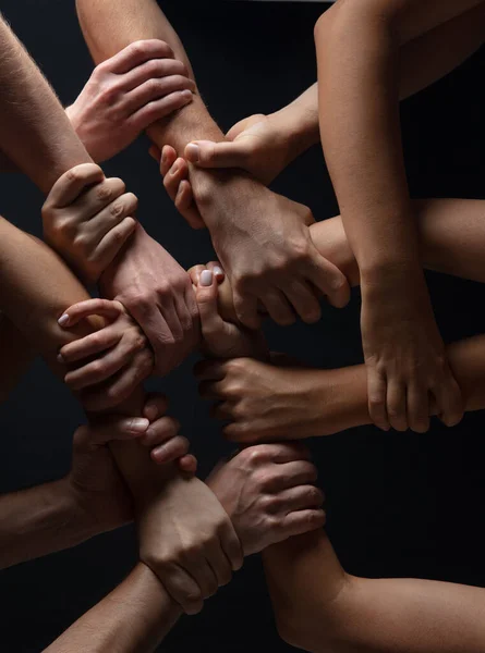 Las manos de la gente se agolpan en contacto aisladas en el fondo negro del estudio. Concepto de relación humana, comunidad, unidad, simbolismo — Foto de Stock