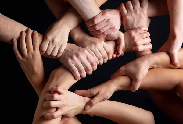 Hands of peoples crowd in touch isolated on black studio background. Concept of human relation, community, togetherness, symbolism