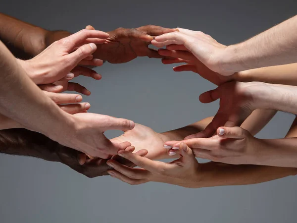 Las manos de la gente se agolpan en contacto aisladas sobre fondo gris del estudio. Concepto de relación humana, comunidad, unidad, simbolismo — Foto de Stock