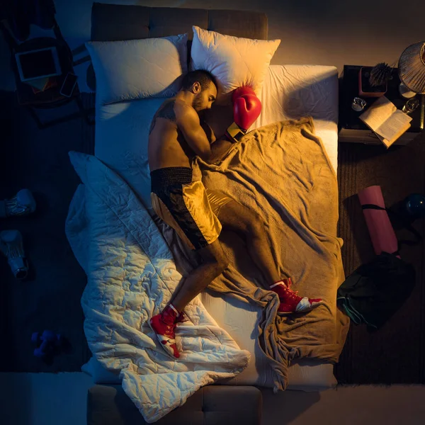 Vista superior del joven boxeador profesional, luchador durmiendo en su dormitorio en ropa deportiva con guantes —  Fotos de Stock