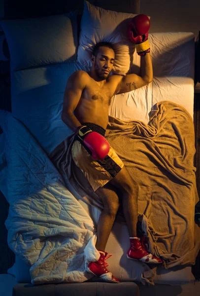 Vista dall'alto del giovane pugile professionista, combattente che dorme nella sua camera da letto in abbigliamento sportivo con i guanti — Foto Stock