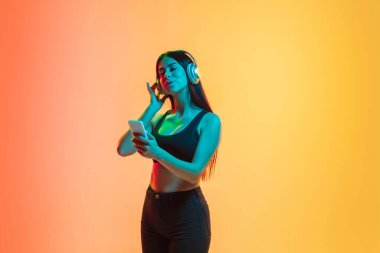 Sarı-turuncu stüdyo arka planında neon ışıklı genç kadın portresi