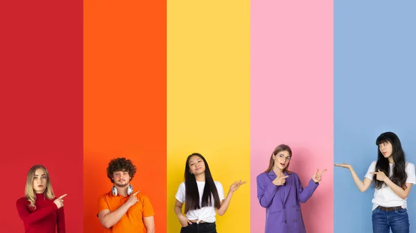 Jóvenes señalando a los lados sobre fondo multicolor. Emociones humanas, concepto de expresión facial. Colores de moda. collage creativo. —  Fotos de Stock