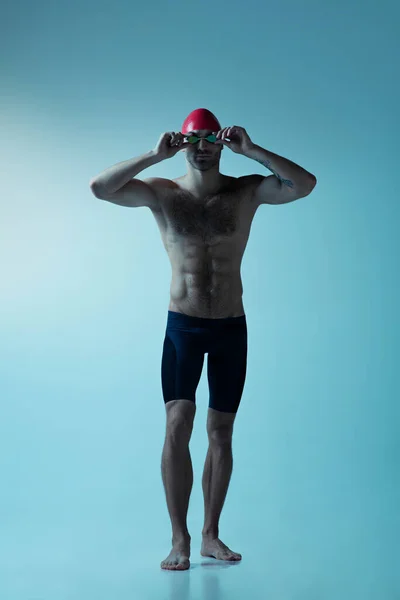 Professional male swimmer with hat and goggles in motion and action, healthy lifestyle and movement concept. Neoned style. — Stock Photo, Image
