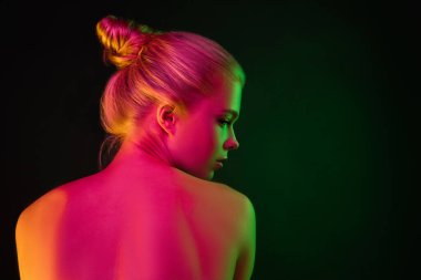 Karanlık stüdyo arka planında neon ışıklı kadın model portresi.