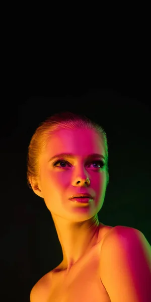 Portrait of female fashion model in neon light on dark studio background. — Stock Photo, Image