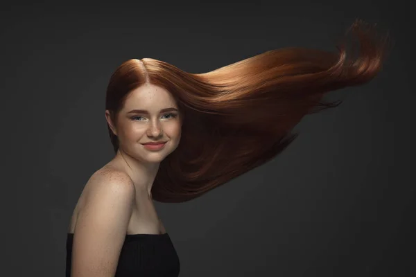 Vacker modell med lång smidig, flygande rött hår isolerad på mörk studio bakgrund. — Stockfoto