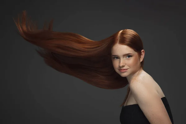 Hermosa modelo con pelo largo y suave, rojo volador aislado sobre fondo oscuro del estudio. — Foto de Stock