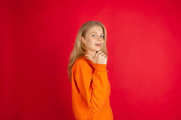 Retrato de una joven mujer caucásica con emociones brillantes aisladas en el fondo rojo del estudio —  Fotos de Stock