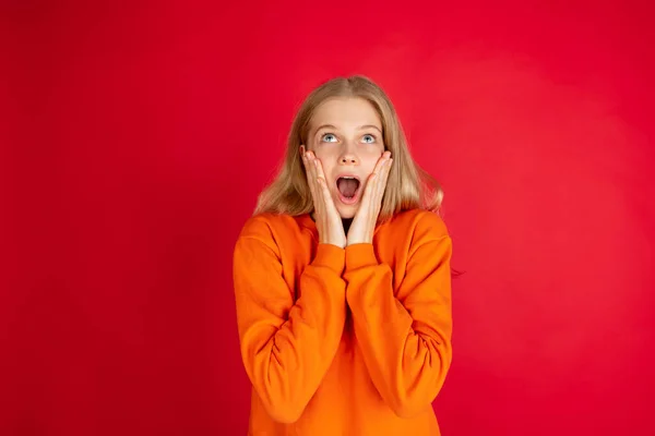 Retrato de una joven mujer caucásica con emociones brillantes aisladas en el fondo rojo del estudio —  Fotos de Stock