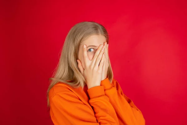 Portrét mladé bělošky s jasnými emocemi izolované na červeném pozadí studia — Stock fotografie