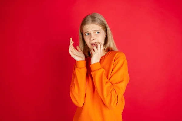 Retrato de una joven mujer caucásica con emociones brillantes aisladas en el fondo rojo del estudio —  Fotos de Stock