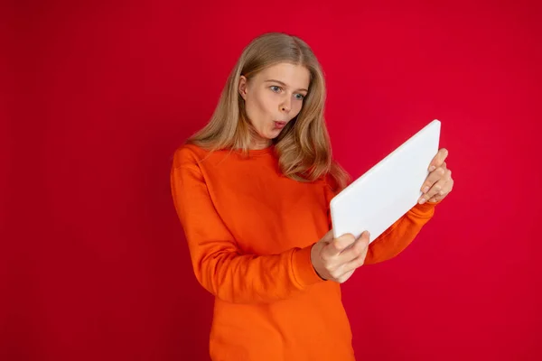 Retrato de una joven mujer caucásica con emociones brillantes aisladas en el fondo rojo del estudio —  Fotos de Stock