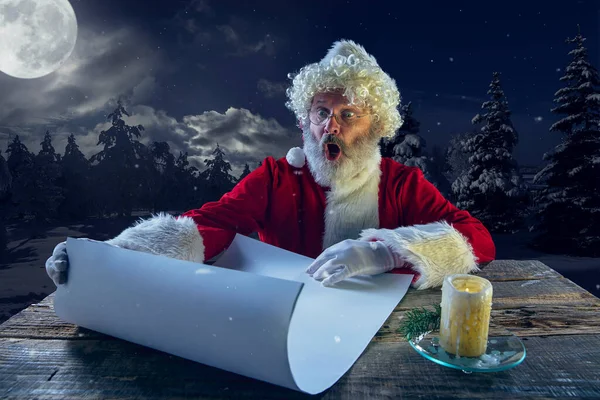 Emotionele Kerstman gefeliciteerd met Nieuwjaar en Kerstmis, het schrijven van een brief, verlanglijstje in middernacht met kaars — Stockfoto