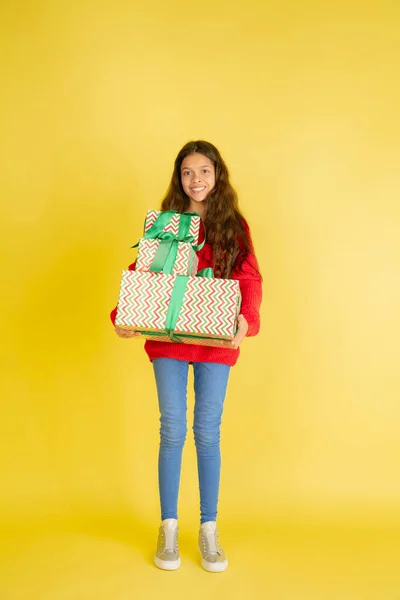 Dar e receber presentes nas férias de Natal. Menina adolescente se divertindo isolada no fundo do estúdio amarelo — Fotografia de Stock