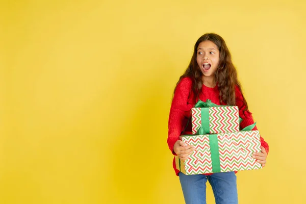 Dar e receber presentes nas férias de Natal. Menina adolescente se divertindo isolada no fundo do estúdio amarelo — Fotografia de Stock
