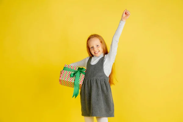 Dar e receber presentes nas férias de Natal. Menina adolescente se divertindo isolada no fundo do estúdio amarelo — Fotografia de Stock