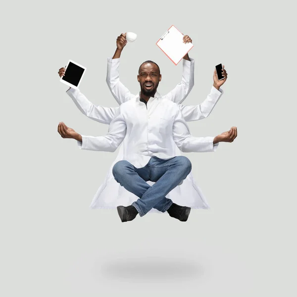 Guapo médico multiarmado levitando aislado sobre fondo gris estudio con equipo — Foto de Stock
