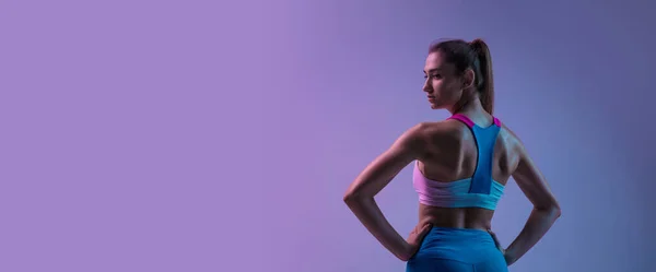 Giovane donna sportiva formazione isolata su sfondo studio gradiente in luce al neon. atletico e aggraziato — Foto Stock