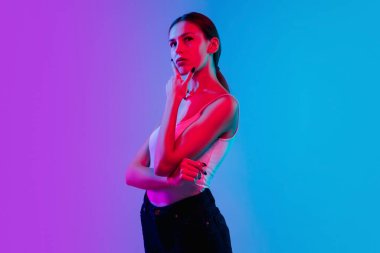 Beyaz kadın portresi, neon ışıklarıyla mavi-mor renkli gradyan stüdyo arka planında.