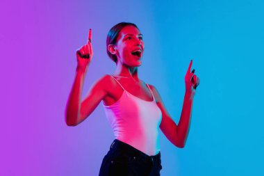 Beyaz kadın portresi, neon ışıklarıyla mavi-mor renkli gradyan stüdyo arka planında.