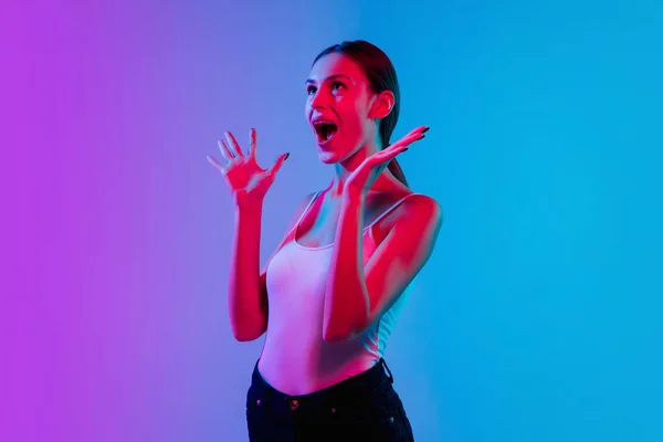 Young caucasian womans portrait on gradient blue-purple studio background in neon light — Stock Photo, Image