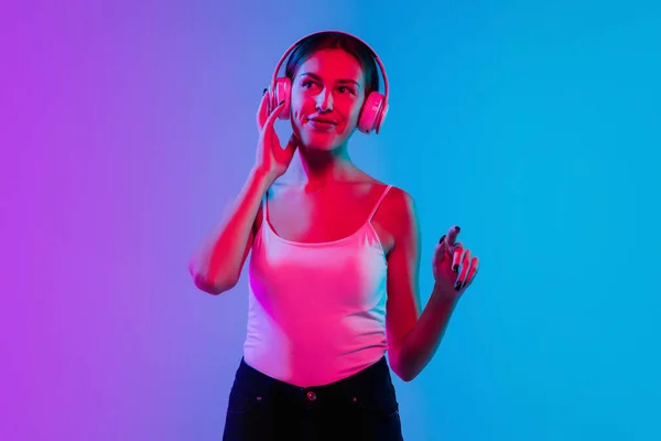 若いですcaucasian女性の肖像画でグラデーション青紫色のスタジオ背景にネオンライト — ストック写真