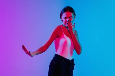 Beyaz kadın portresi, neon ışıklarıyla mavi-mor renkli gradyan stüdyo arka planında.