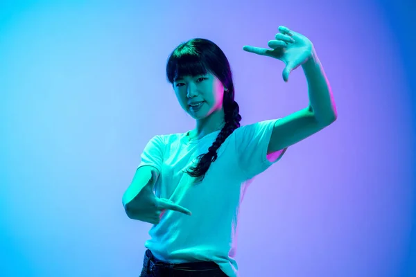 Mladé asijské ženy portrét na gradient blue-purple studio pozadí v neonovém světle — Stock fotografie